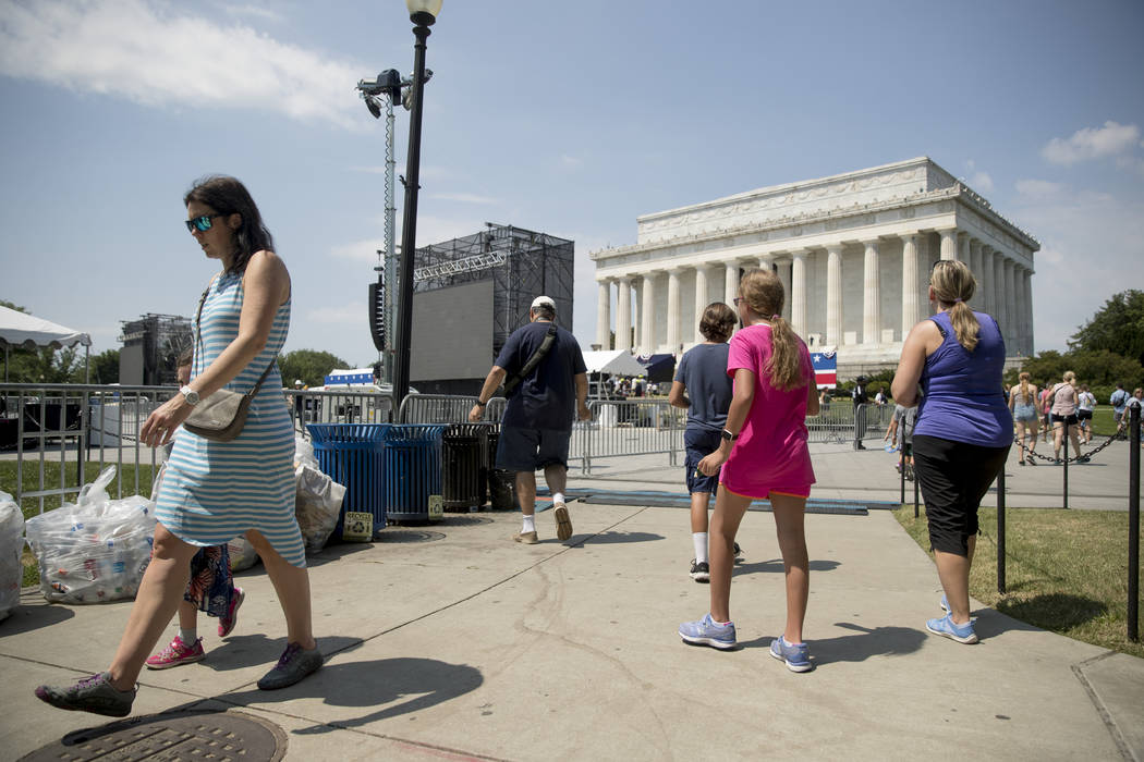 Visitors to the National Mall walk near the Lincoln Memorial as workers set up for President Do ...