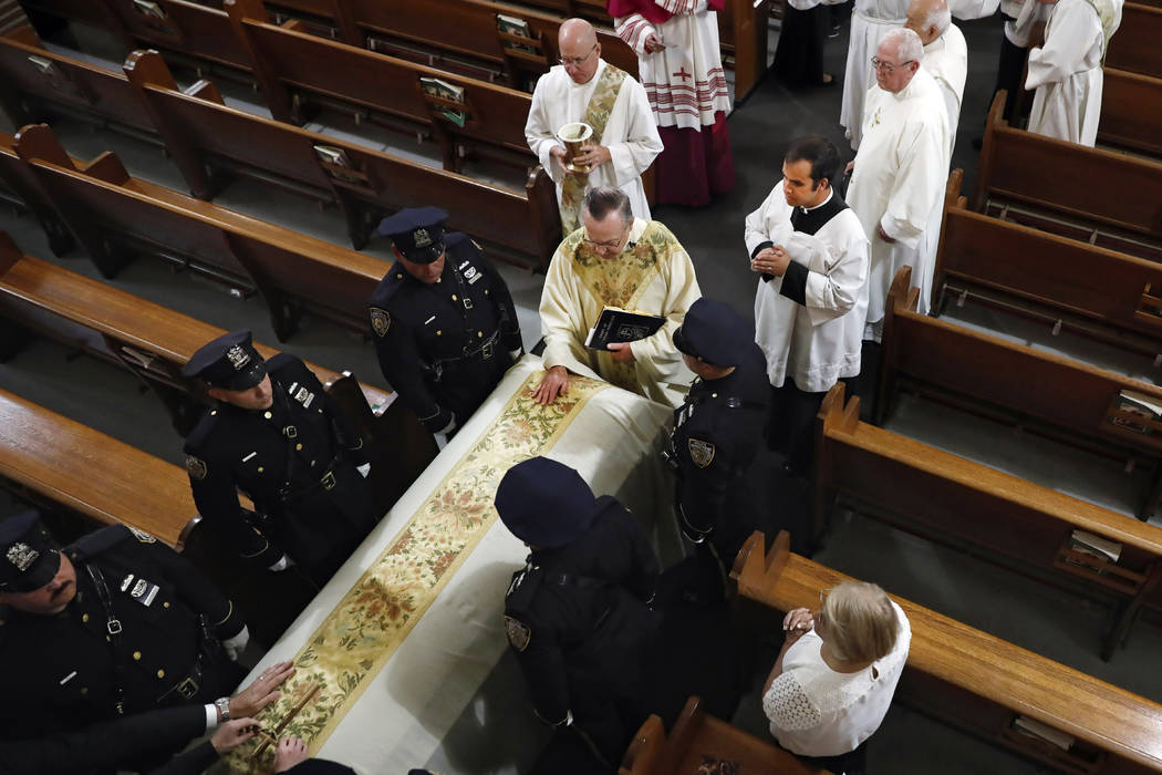 Rev. John P. Harrington blesses the casket during the funeral ceremony for Detective Luis Alvar ...