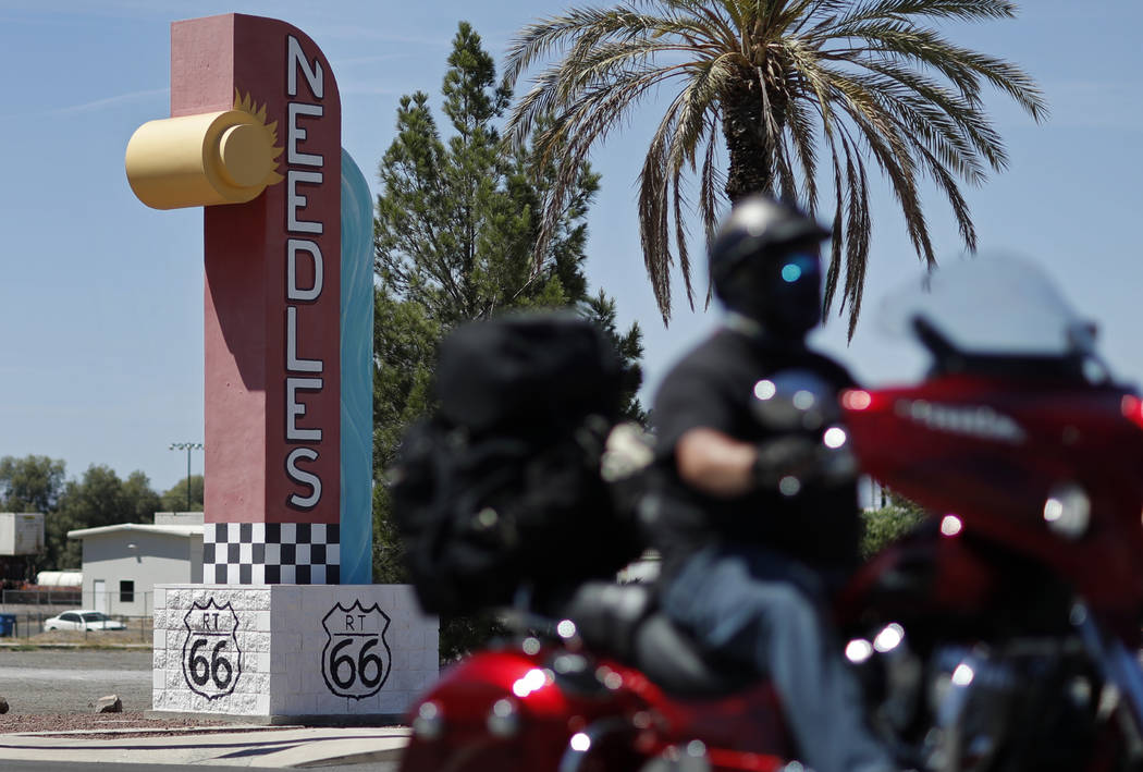 In this June 27, 2019, photo, a motorcyclist drives by a sign along the old Route 66 in Needles ...