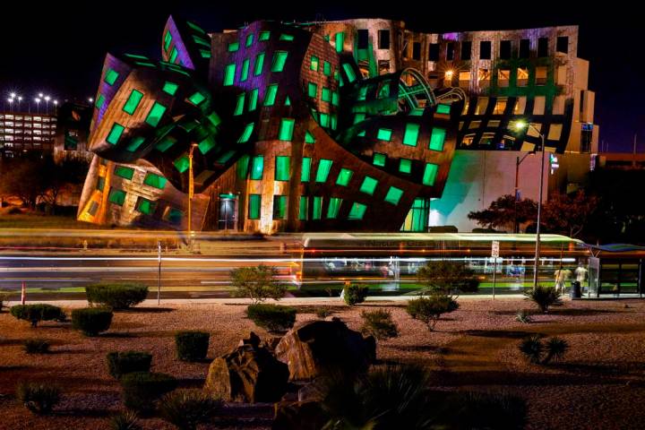 The windows are bathed in green from within the Keep Memory Alive Event Center designed by reno ...