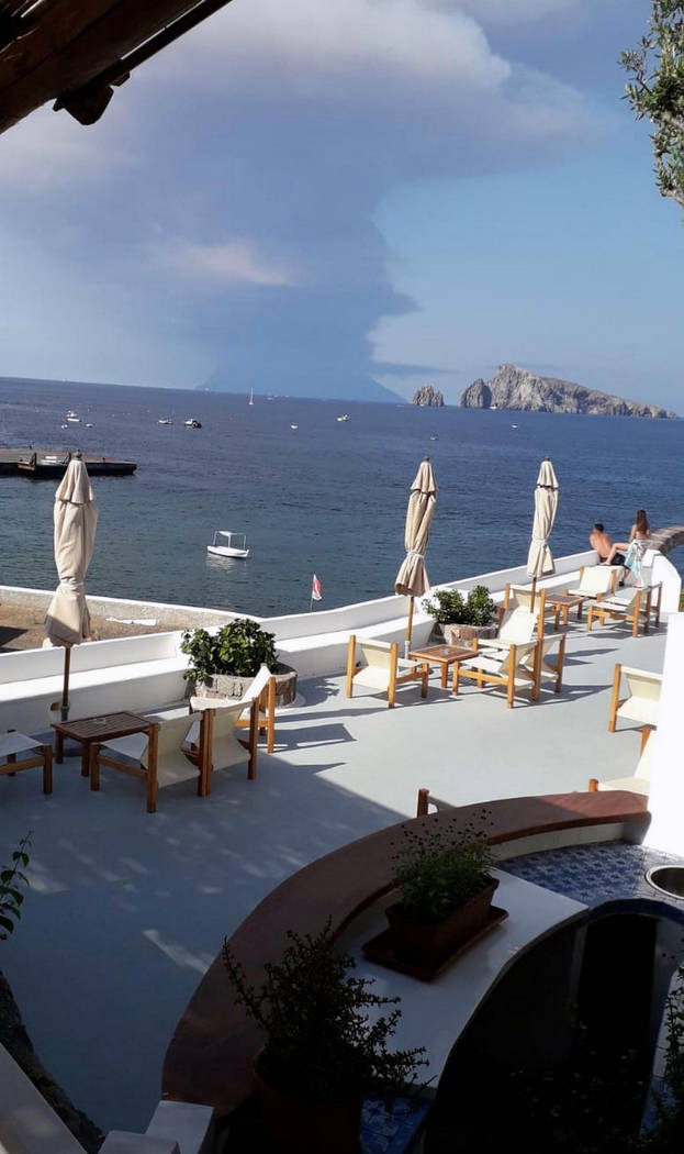 Smoke billows from the volcano on the Italian island of Stromboli, background, following an eru ...