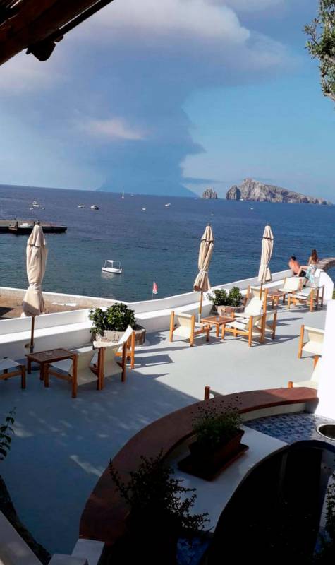 Smoke billows from the volcano on the Italian island of Stromboli, background, following an eru ...