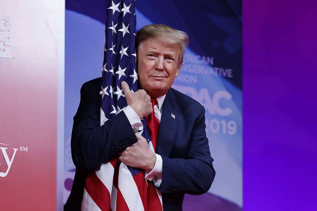 President Donald Trump hugs the American flag as he arrives to speak at Conservative Political ...