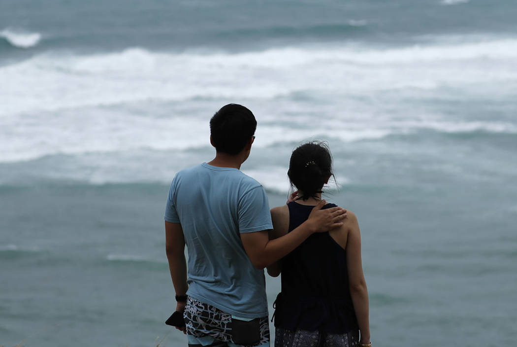 Dan Wong, left, and Cassie Tarleton watch waves crash along the coastline ahead of Hurricane La ...