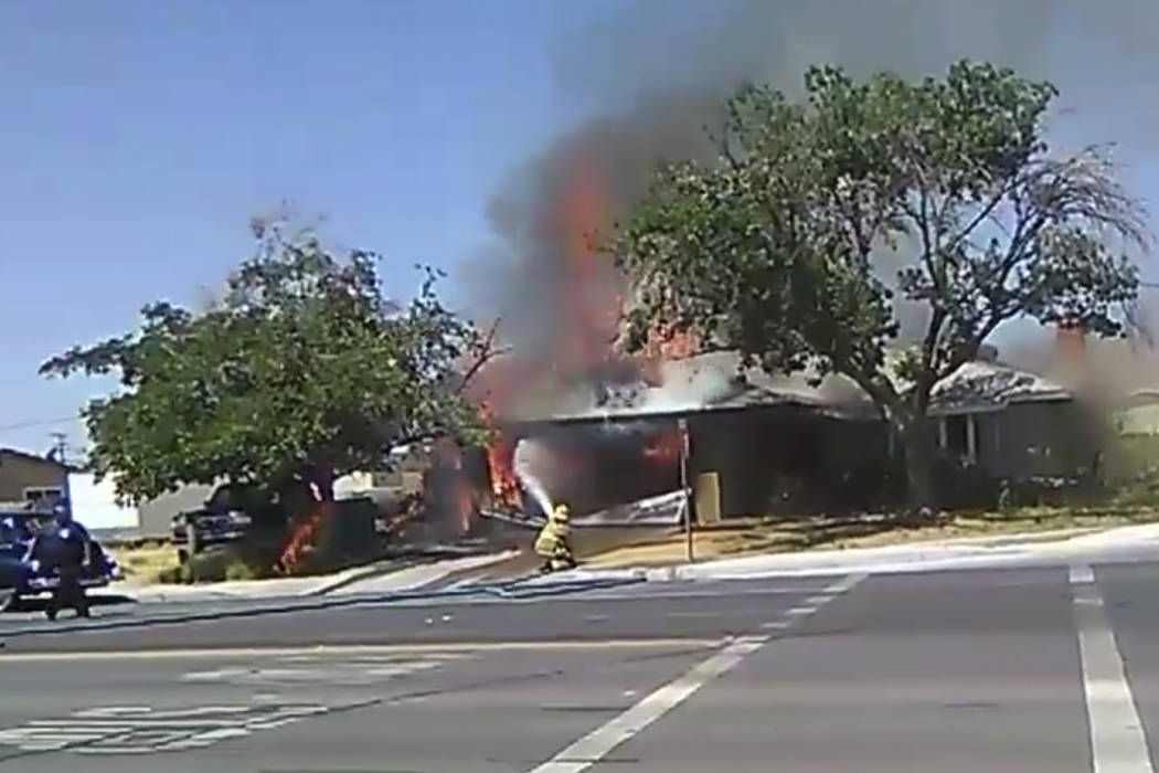 In an image taken from video, a firefighter works to extinguish a house fire, Thursday, July 4, ...