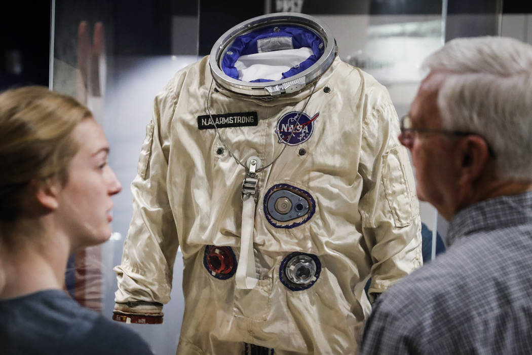 Visitors stand before the spacesuit worm by astronaut Neil Armstrong that was used on his Gemin ...