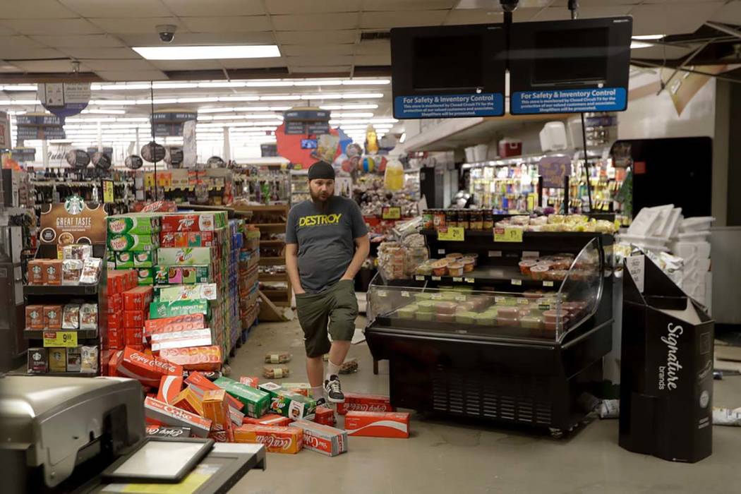 A worker steps over merchandise that is scattered on the floor of a Albertson's grocery store S ...