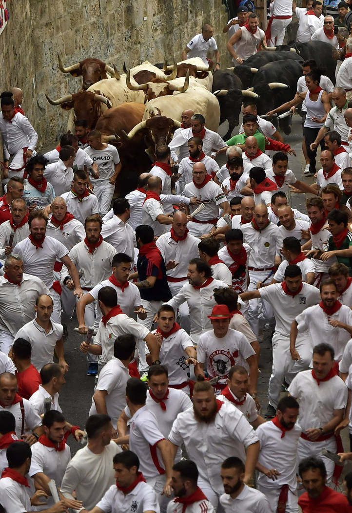 Revellers run next to fighting bulls during the running of the bulls at the San Fermin Festival ...