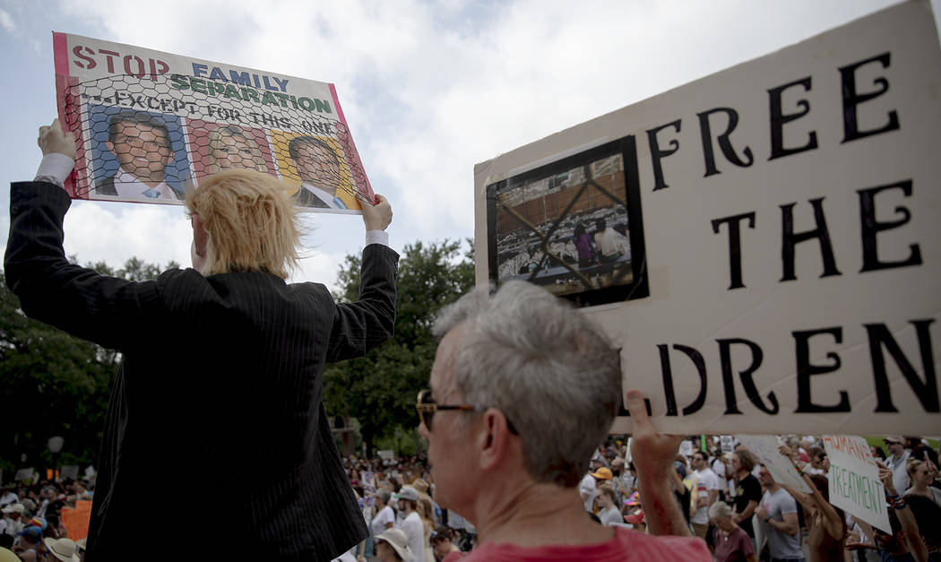 Heidi Turpin, left, dressed as President Donald Trump, holds up a sign next to her husband, Jim ...