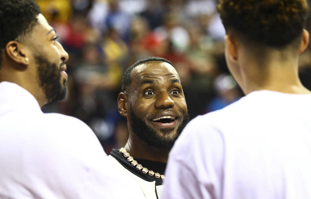 Los Angeles Lakers' LeBron James, center, talks with teammates Anthony Davis, left, and Kyle Ku ...