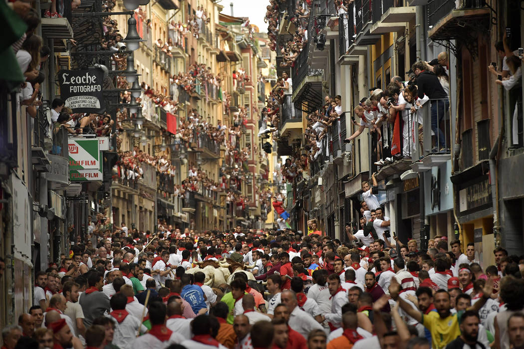 Revellers run next to fighting bulls from Cebada Gago ranch during the running of the bulls at ...