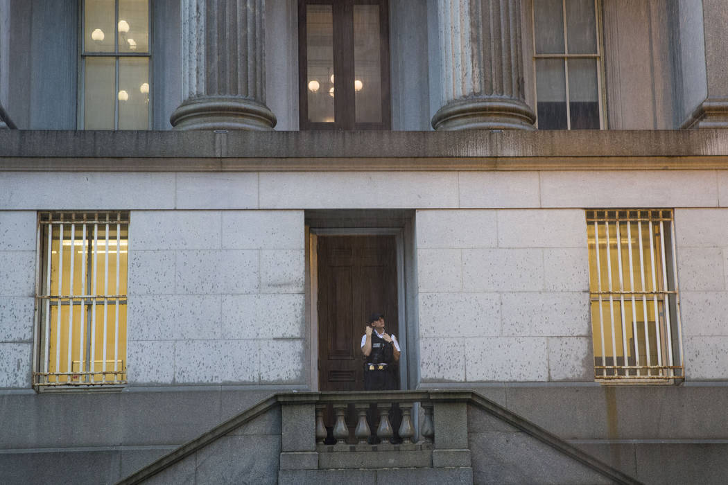 A Uniformed Division Secret Service officer looks up at the rain as he takes shelter in a doorw ...