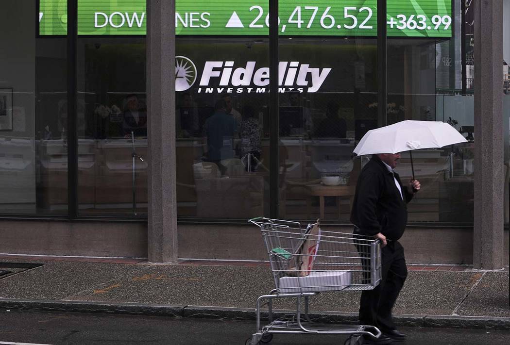 In a June 18, 2019, photo a man pulls a grocery cart as he walks in the rain past the stock tic ...