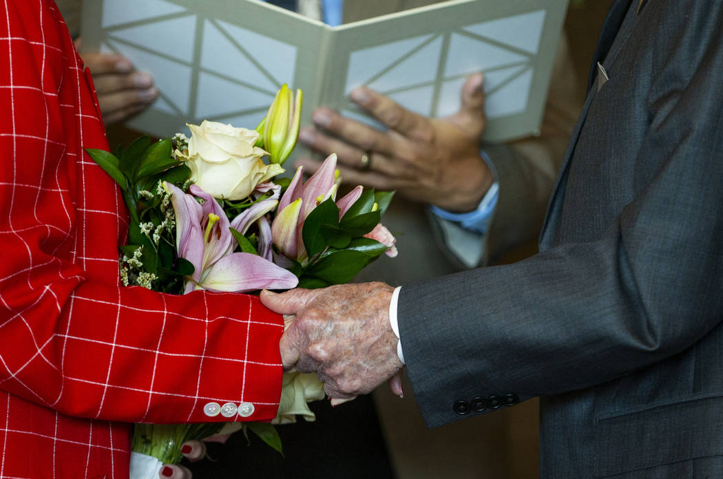 Gail and Donna Andress hold hands during a renewal of vows ceremony celebrating their 75th wedd ...