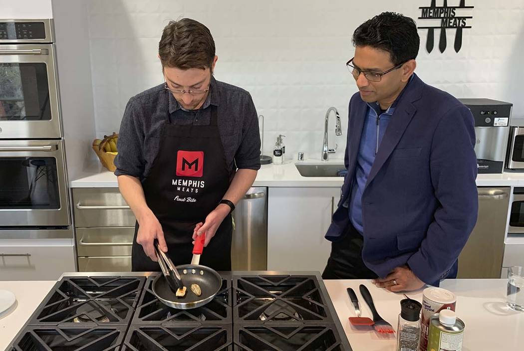 Memphis Meats CEO Uma Valeti, right, watches chicken produced in a laboratory from chicken cell ...