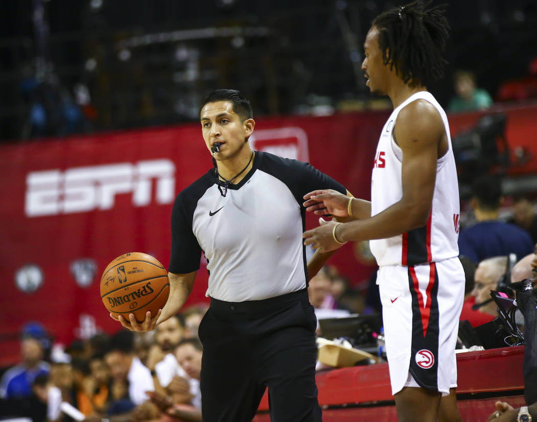 Referee Omar Bermudez, left, stands next to Atlanta Hawks' Tahjere McCall while officiating a g ...