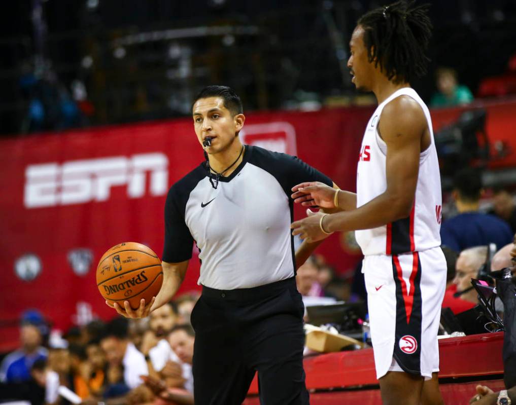 Referee Omar Bermudez, left, stands next to Atlanta Hawks' Tahjere McCall while officiating a g ...