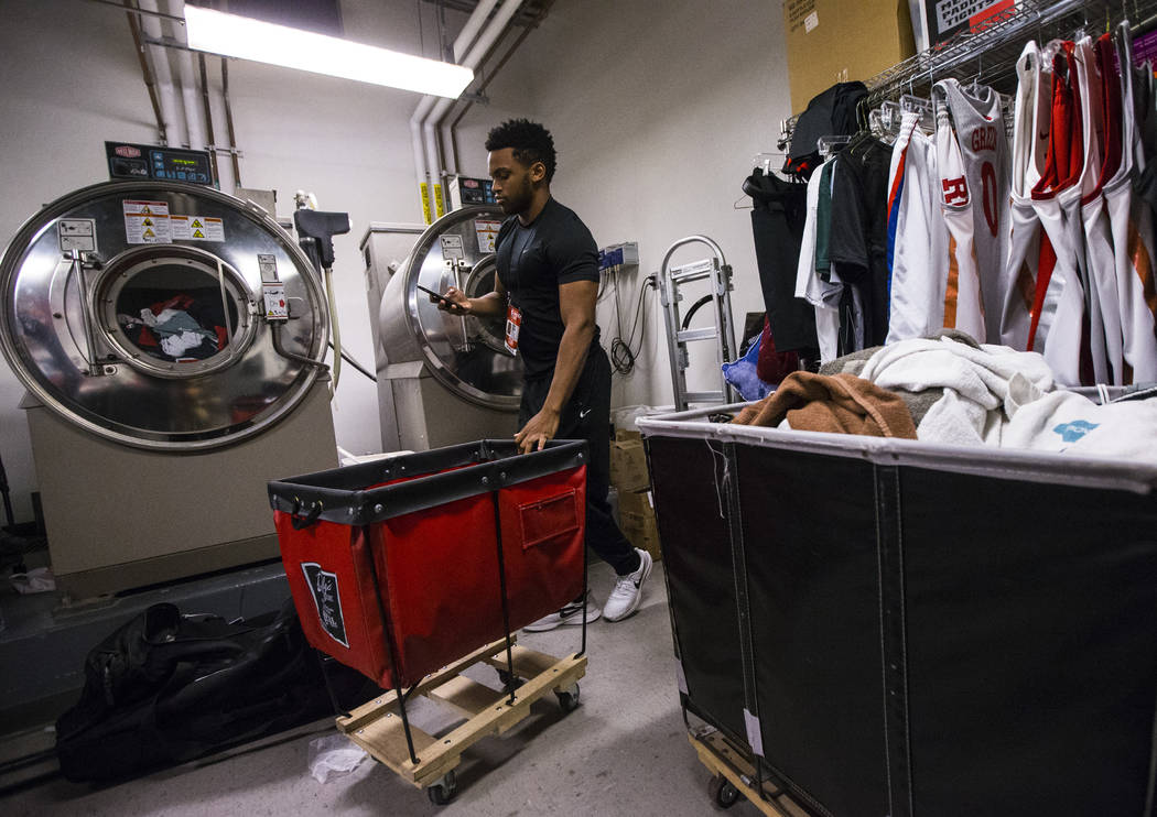 UNLV student Wesley Wharton checks the time on his phone while organizing clothes for NBA teams ...