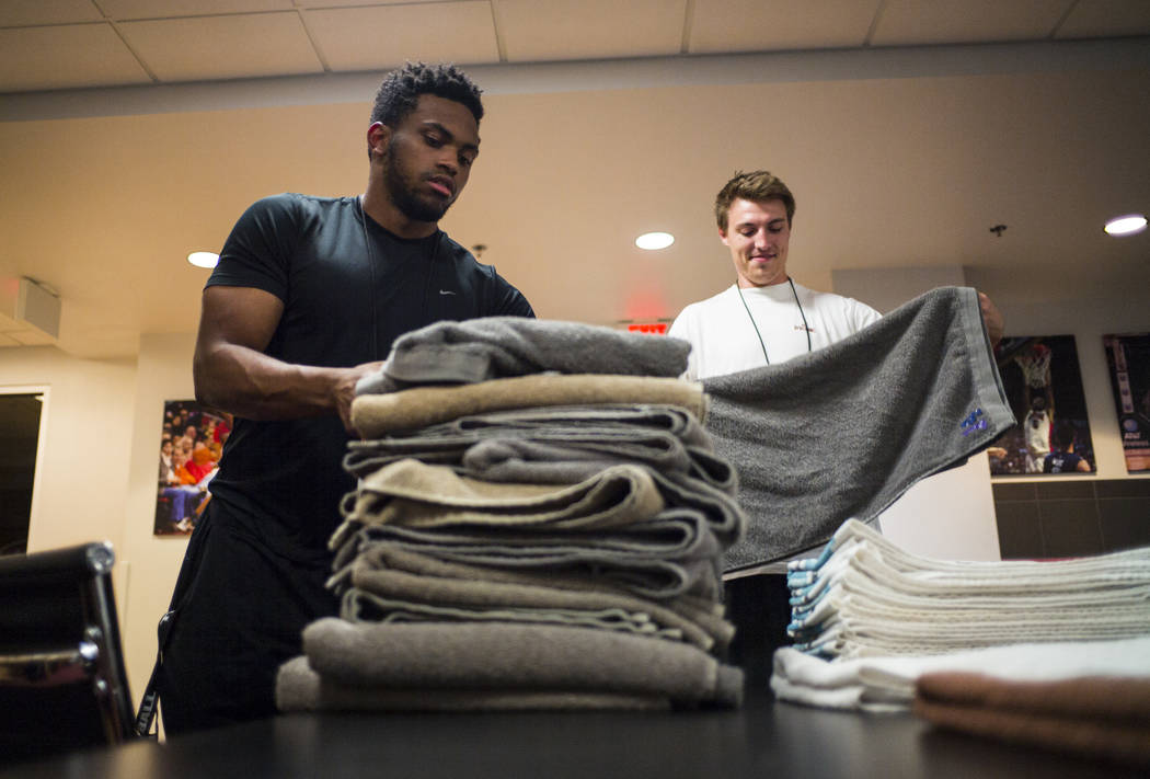 UNLV students Wesley Wharton, left, and Devin James organize towels for the UNLV basketball tea ...
