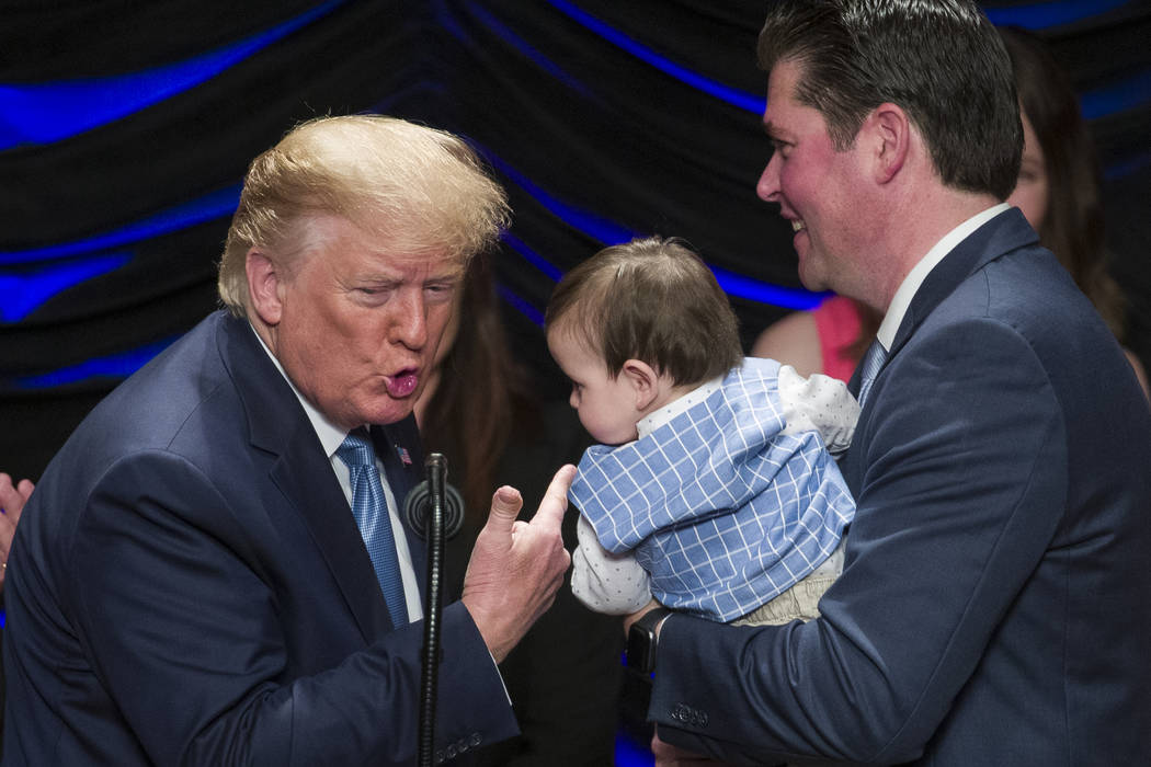 President Donald Trump reacts after kissing Hudson Nash, being held by father Andrew Nash, as T ...