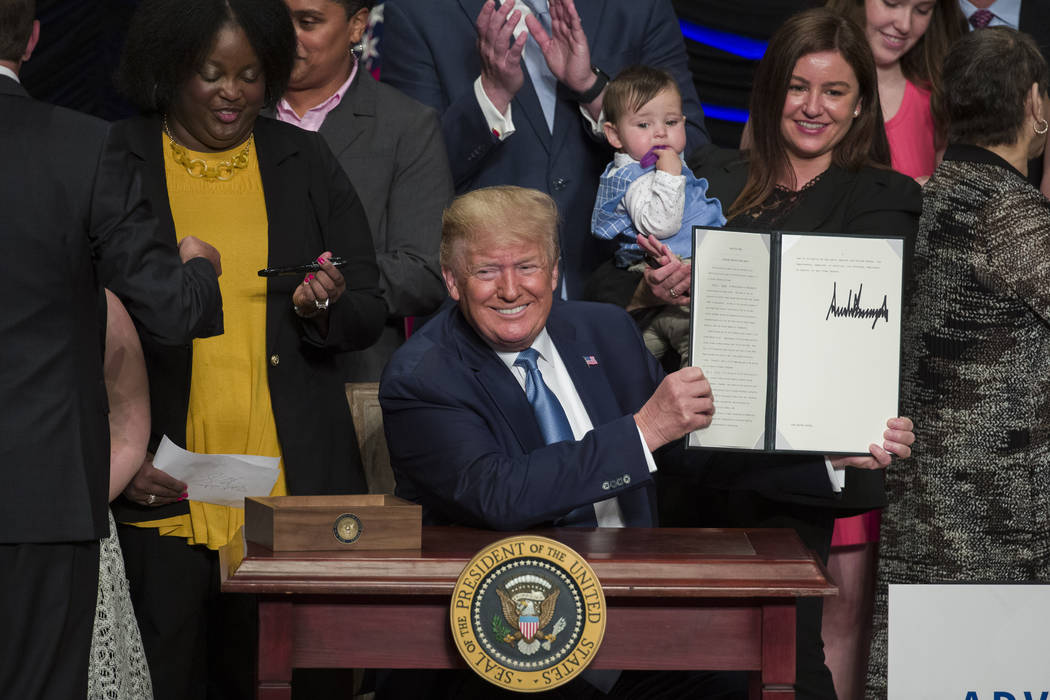 President Donald Trump holds up a signed executive order about kidney health at the Ronald Reag ...