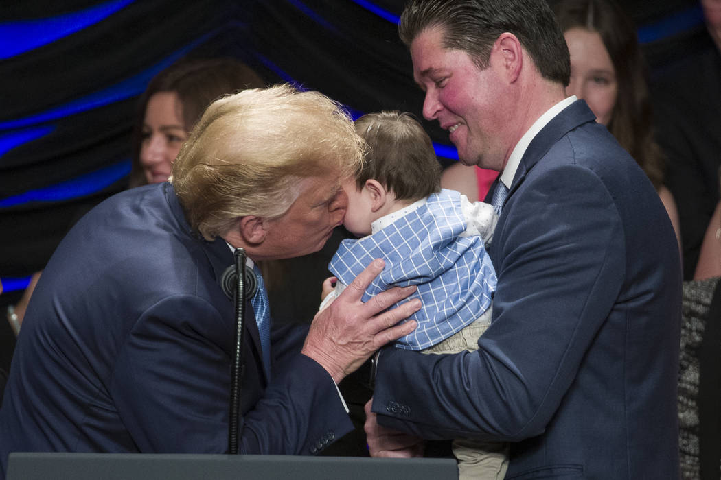 President Donald Trump kisses Hudson Nash, being held by father Andrew Nash, as Trump speaks ab ...