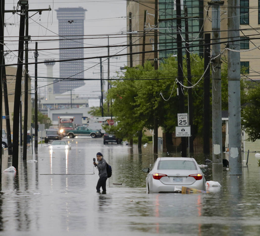 A person crosses a flooded Drexel Drive as heavy rain falls, Wednesday, July 10, 2019, in New O ...