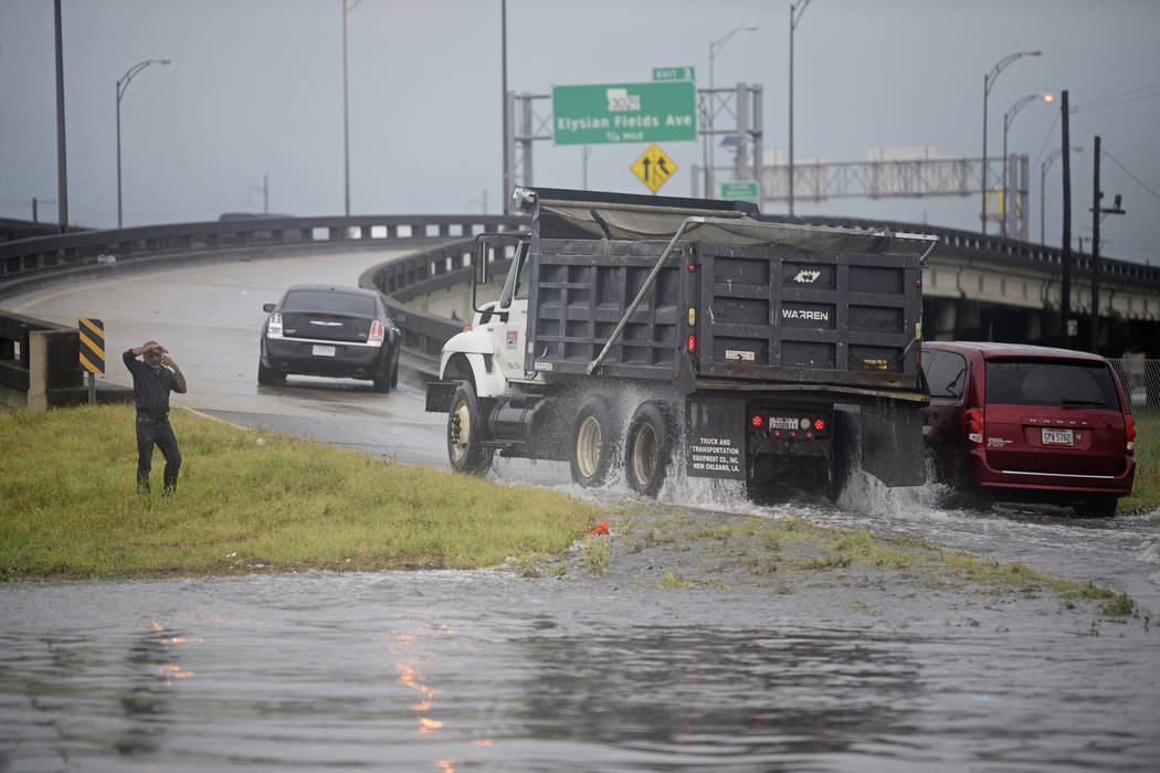 A stuck motorist makes a cellphone call as truck speeds through flooding at the intersection of ...