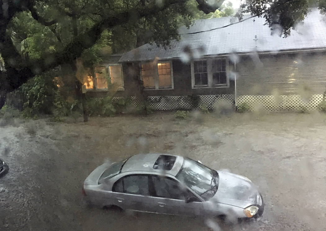 In this photo made available by Kshithij Shrinath, flood waters surround a car as heavy rain fa ...