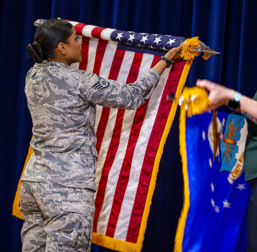Staff Sgt. Britneyrose Ward rolls up the American flag at Nellis Air Force Base on Friday, July ...