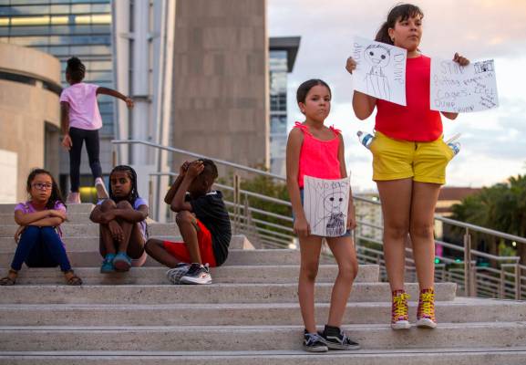 Diana Tarin, 8, left, and her sister Cecilia, 11, stand with handmade signs during Lights for L ...