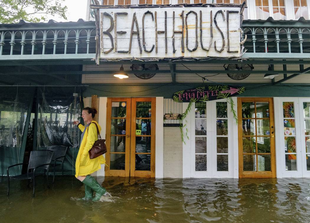 Aimee Cutter, the owner of Beach House restaurant, walks through water surge from Lake Pontcha ...