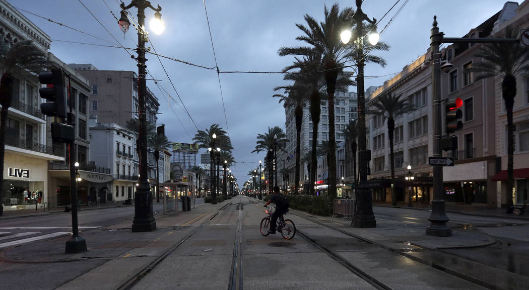 A man rides a bicycle on Canal Street Saturday, July 13, 2019, in New Orleans, as Tropical Stor ...