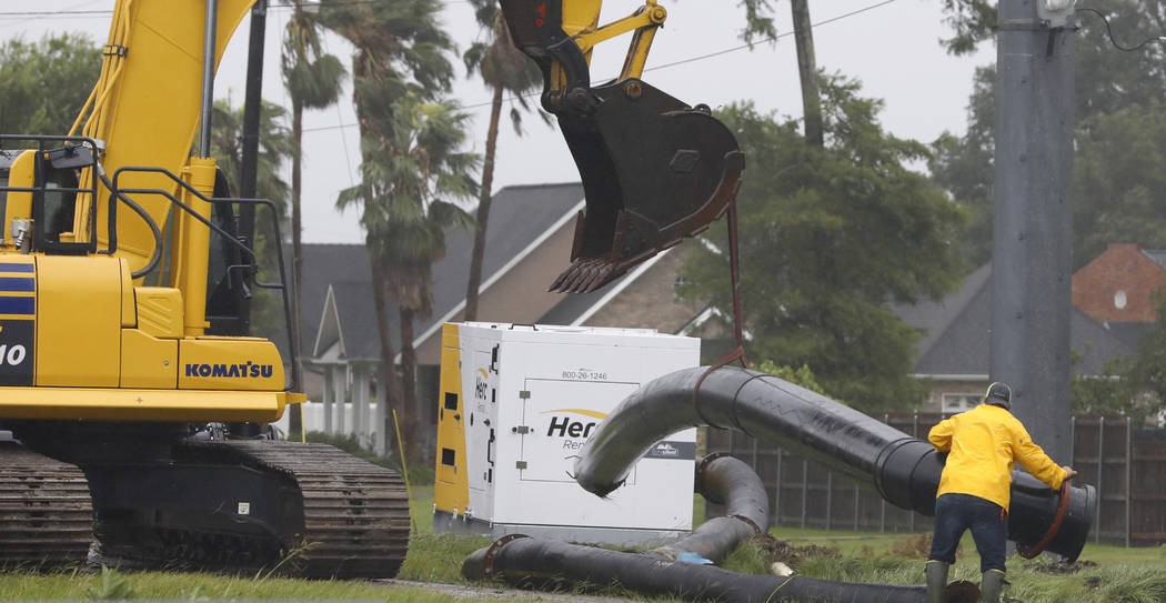 A worker maneuvers a section of pipe to the ground as a crew raced to install drainage pumps in ...