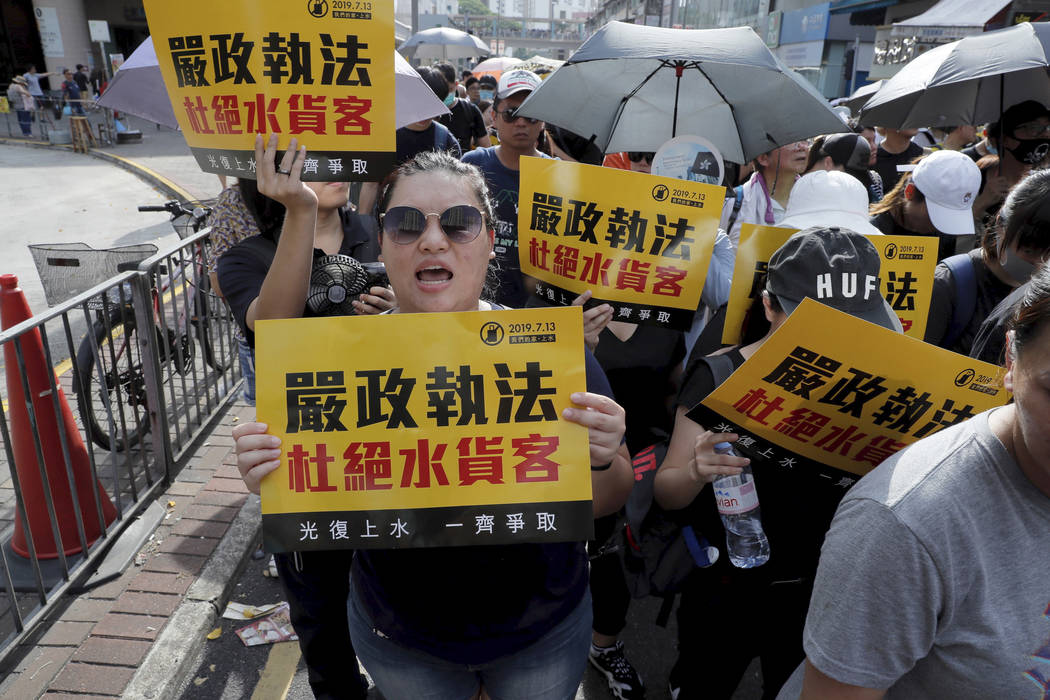 Protesters hold up words that read: "Strict enforcing of law against smugglers of grey goo ...