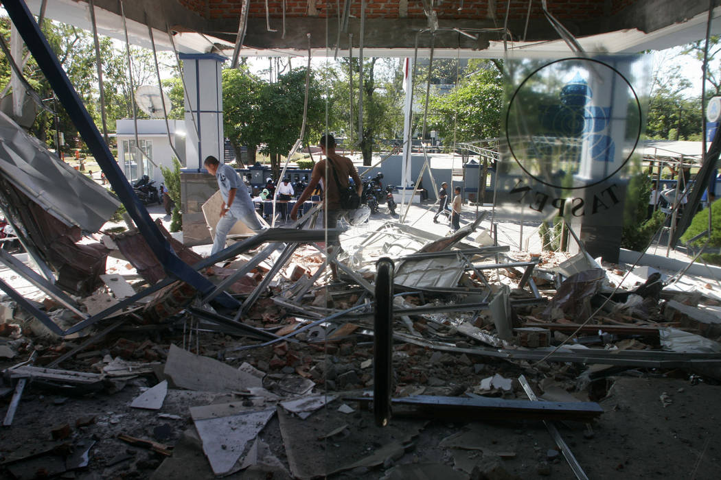 People walk through debris from Wednesday's strong earthquake at an office building in Banda Ac ...