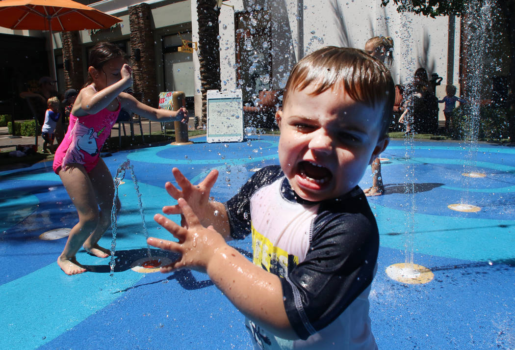 Children, including Caleb Lugrand, 2, right, of Las Vegas play at a splash pad on a hot day at ...