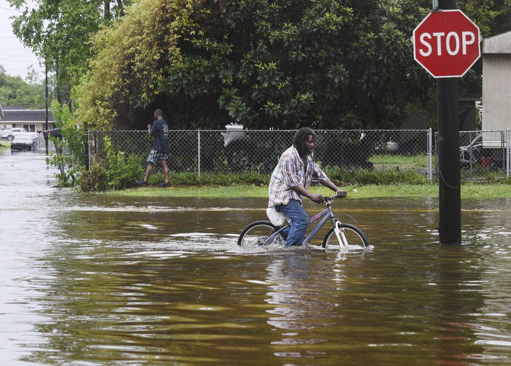 A man tries to bike through the flooding from the rains of storm Barry on LA Hwy 675 in New Ibe ...