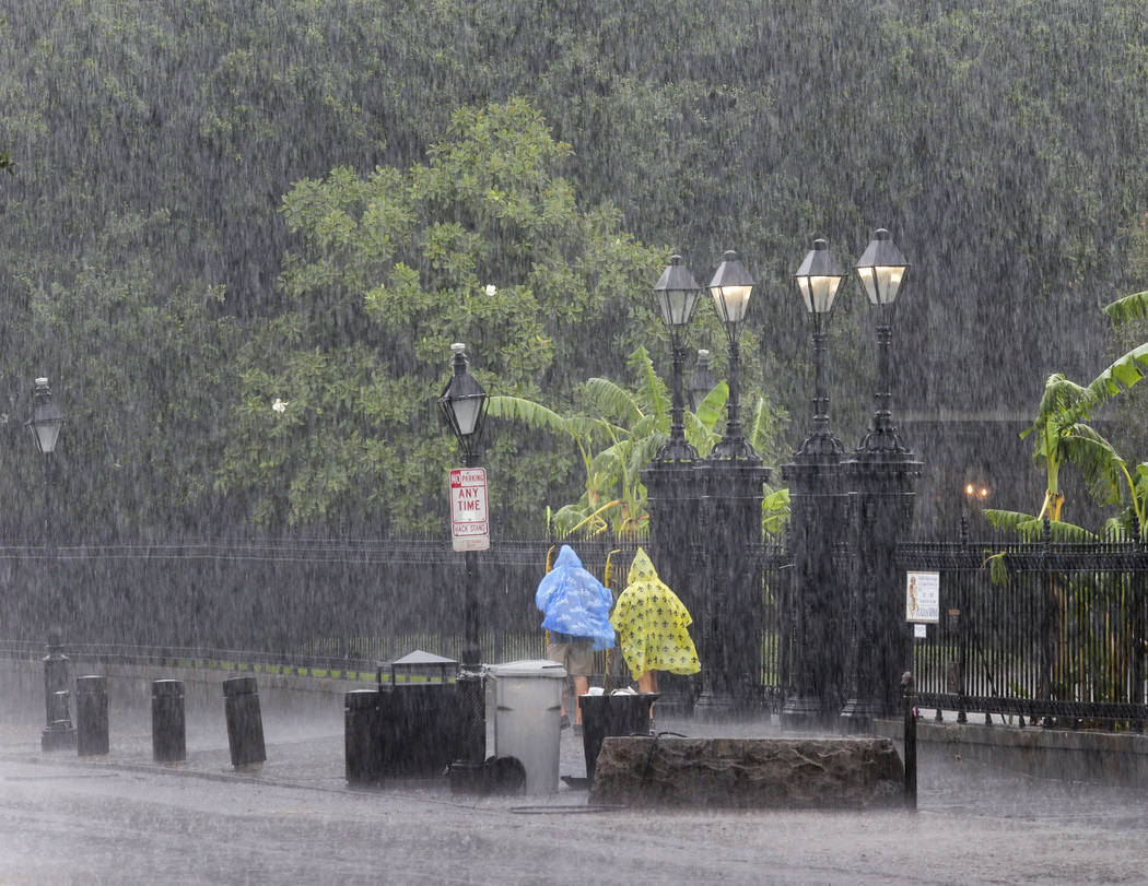 People walk on a street during a downpour at the French Quarter in New Orleans, Sunday, July 14 ...