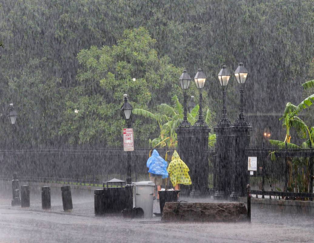 People walk on a street during a downpour at the French Quarter in New Orleans, Sunday, July 14 ...