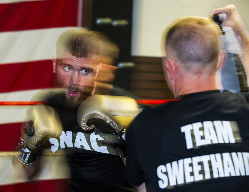 Boxer Caleb Plant, IBF super middleweight champion, left, readies to strike a pad held by his d ...