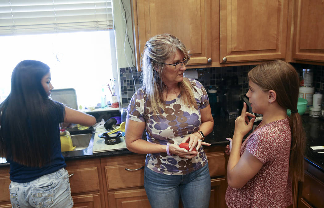 Anita Stephens, center, makes dinner with adopted daughters Serra Stephens, 14, left, and Abi S ...