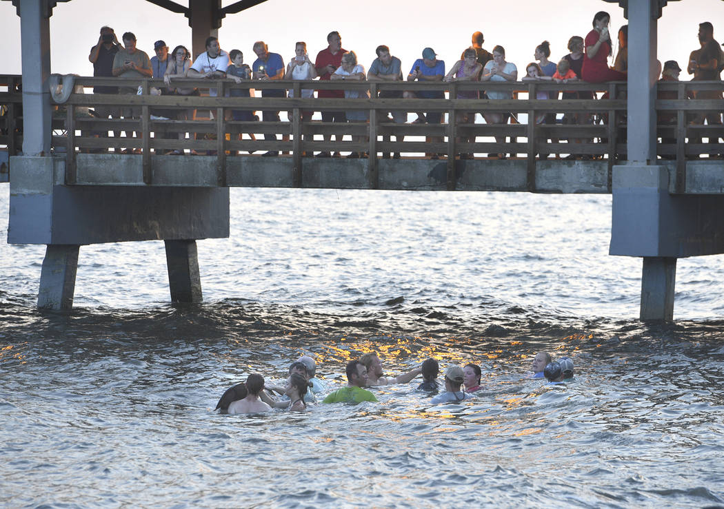 People on the St. Simons pier watch as Georgia Department of Natural Resources personnel and be ...