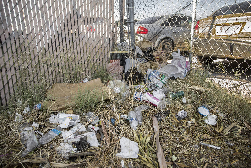 Trash and other debris pile up against a fence on West Bonanza Road near North Martin Luther Ki ...