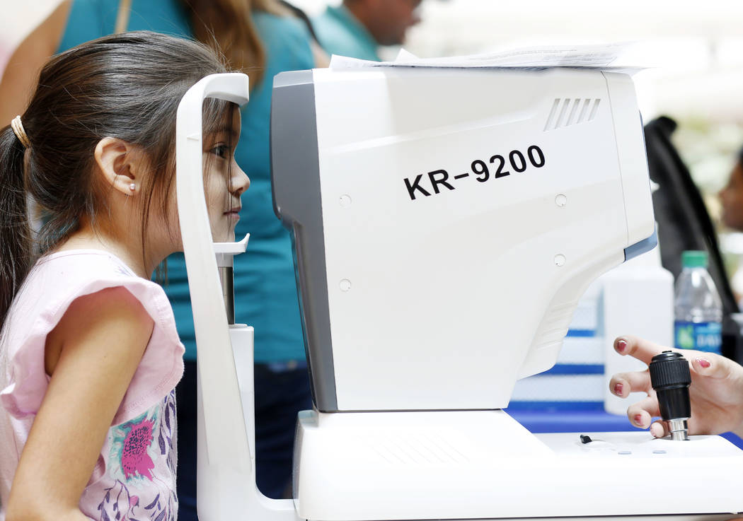 Lillian Daunas, 6, receives an eye check during the annual Cox Back to School Fair at the Galle ...