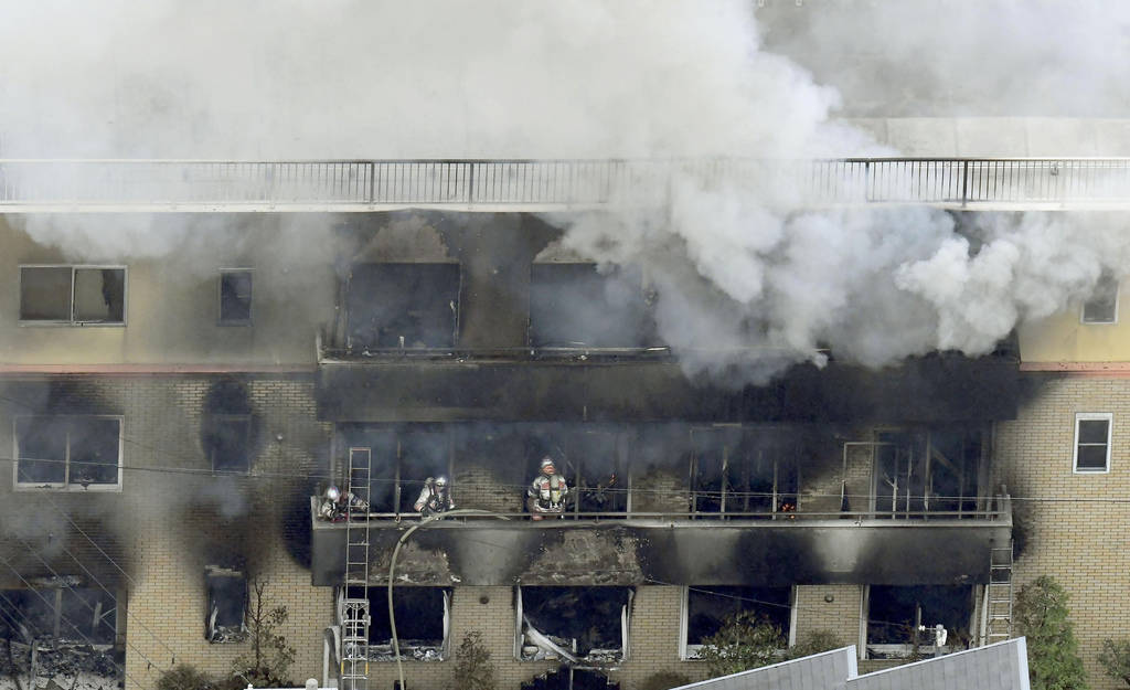 Firefighters work as smoke billows from a three-story building of Kyoto Animation in a fire in ...