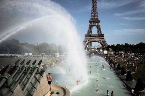 People cool off in the fountains of the Trocadero gardens, in front of the Eiffel Tower, in Par ...