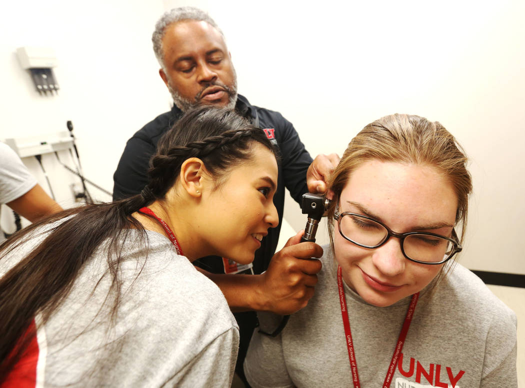 Dr. Aaron Bellow Jr., 45, checks the ear of Anabelle Carino, 17, right, as Victoria Tarango, 1 ...