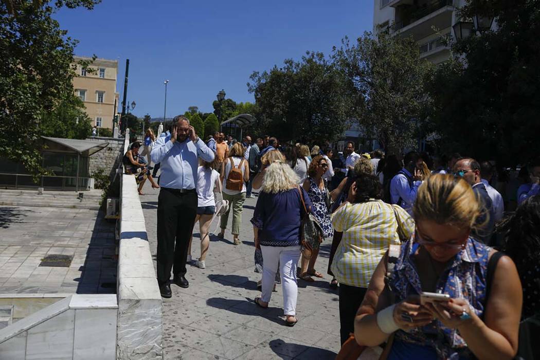 People speak on their phones as they stand outside the building they work in, after a strong ea ...