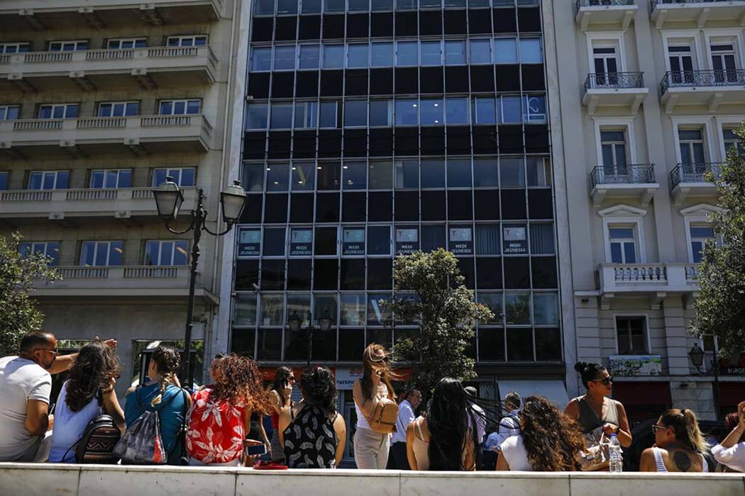 People speak on their phones as they stand outside the building they work in with the Greek Par ...